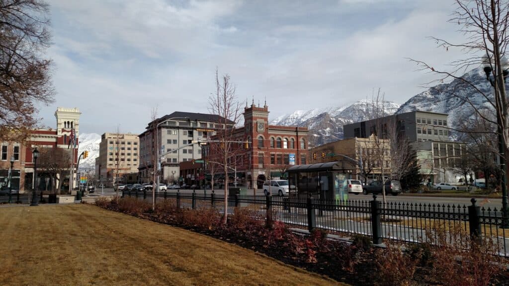 A cityscape in Provo with buildings, trees, and mountains in the background, showcasing a clean urban area with no visible ju.