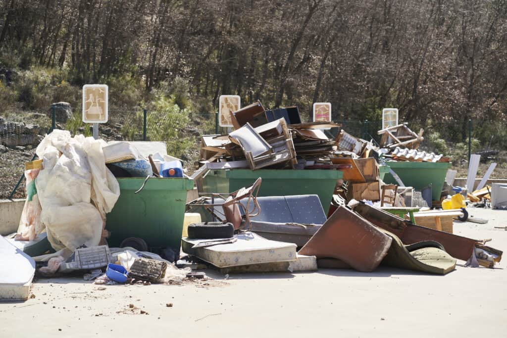 An image of overflowing dumpsters filled with various types of junk, including furniture, appliances, and debris, ready for r.