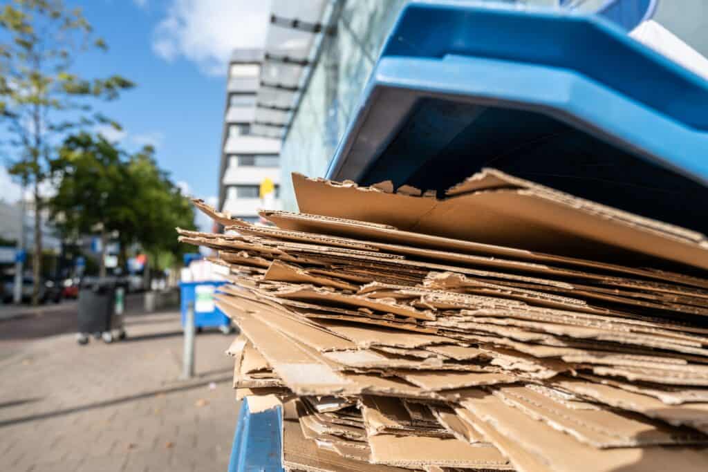An image of a large pile of flattened cardboard boxes ready for junk removal and recycling services outside a modern building.