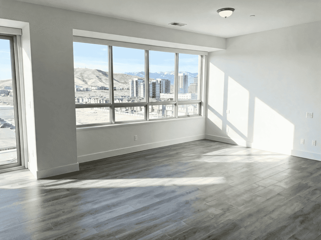 Empty apartment with large windows and city skyline view, ready for cleaning or renovation services.