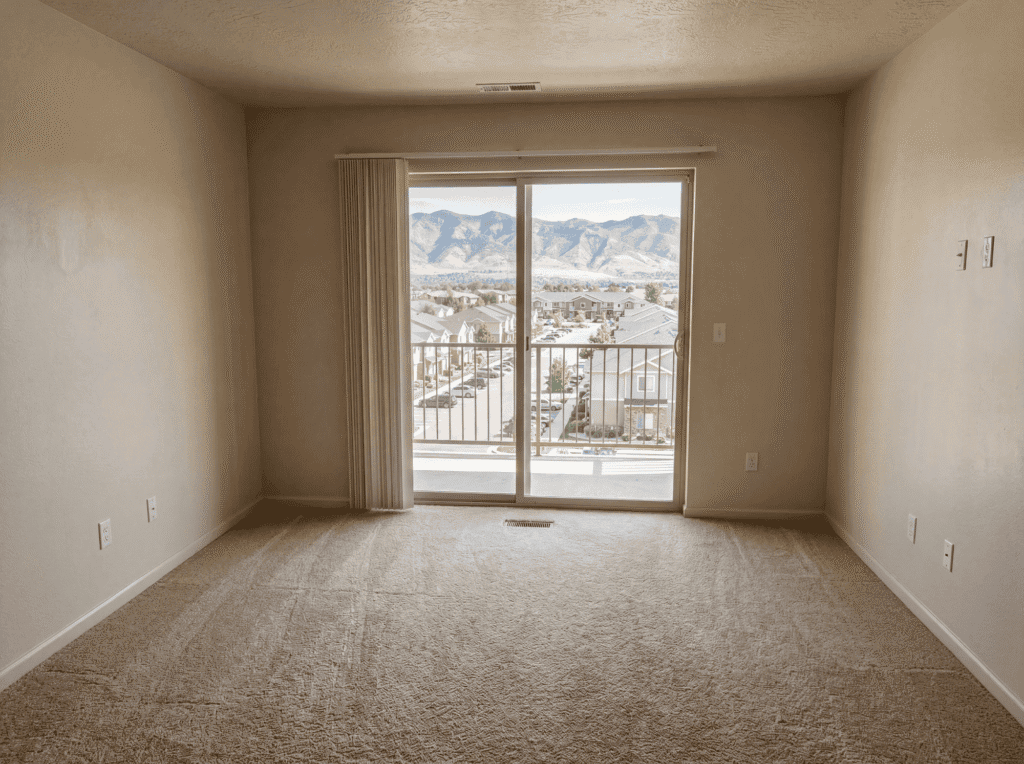 Empty living room with sliding glass door and mountain view, ready for junk removal or renovation.