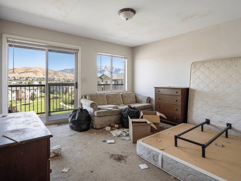 An untidy living room with trash, boxes, and furniture removal in progress, showcasing the need for professional junk removal.