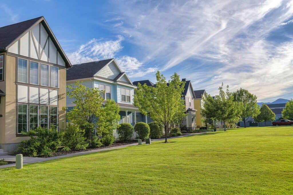 A row of contemporary houses with lush green lawns and trees in a peaceful suburban setting.