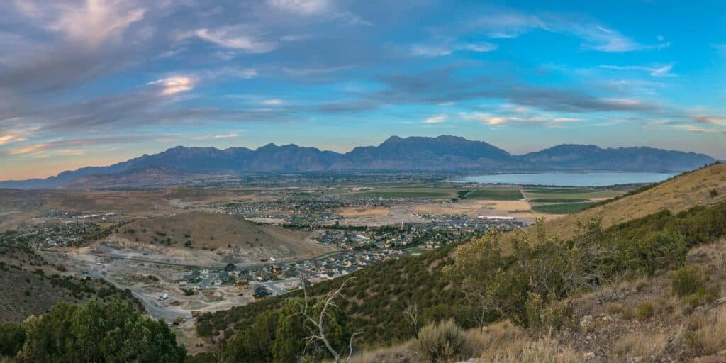 Mountain landscape with a valley and a body of water under a partly cloudy sky.