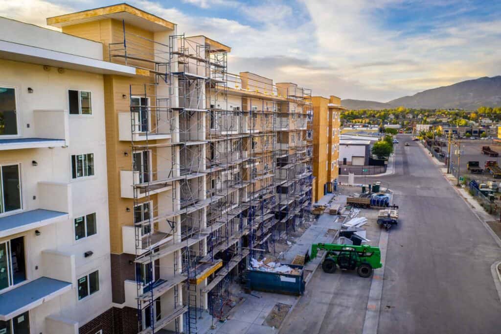 Construction site of a new apartment building with scaffolding and building materials in progress.