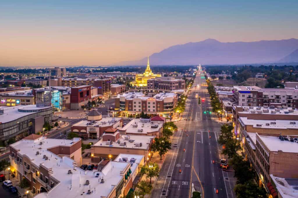 Aerial view of a city street with buildings in Ogden Utah illuminated at sunset.