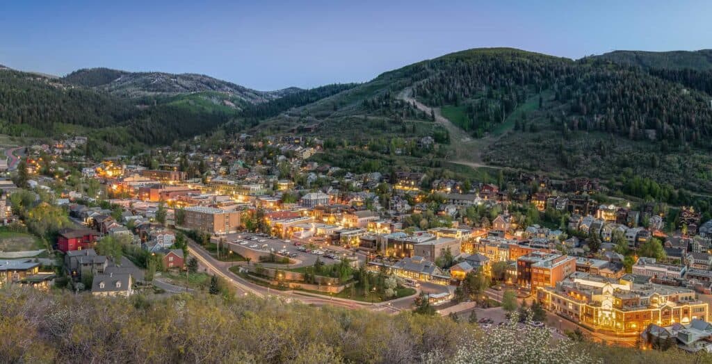 Scenic view of a small town nestled in the mountains during evening with city lights.