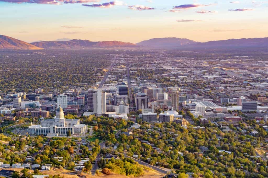 Aerial view of a bustling city with skyscrapers and green parks during sunset.